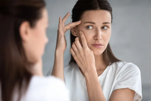 Acne-Mix-IV-Therapy-Specialist A young woman looks at acne on her face. Get IV Therapy for acne from Guerda Johnson, FNP-C in Tyler East Texas Area.