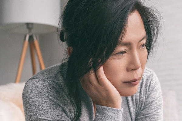 Adrenal-Fatigue-Doctor A middle-aged asian woman sitting on her couch, resting her head on her hand, suffering from adrenal fatigue. Get treatment for adrenal fatigue syndrome from Guerda Johnson, FNP-C in Tyler East Texas Area.