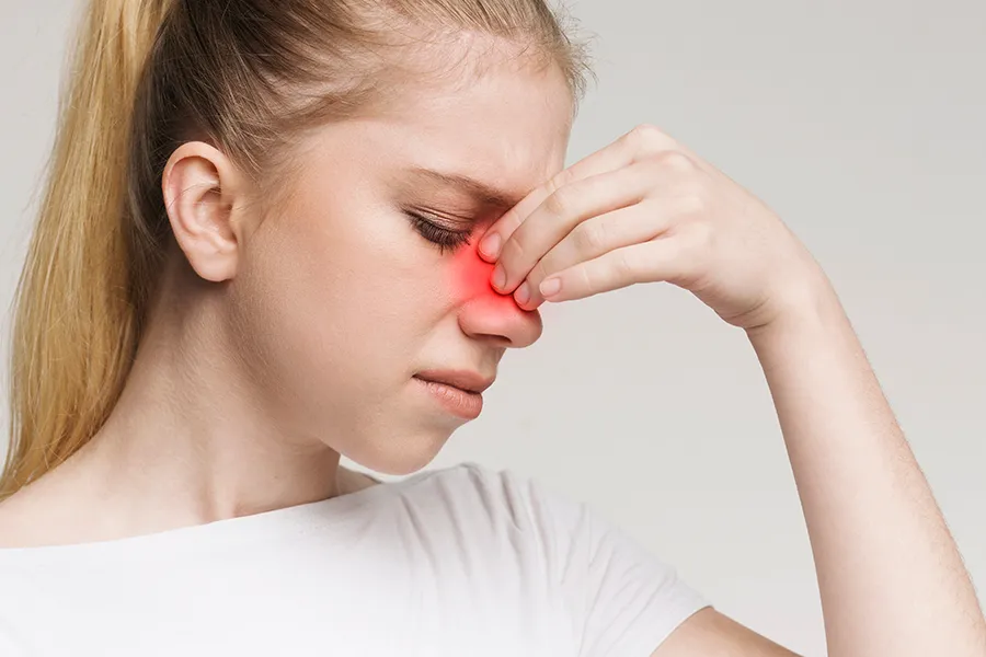 Allergic-Rhinitis-Clinic A woman grimaces and rubs the bridge of her nose due to sinus irritation. Get treatment for allergic rhinitis from Guerda Johnson, FNP-C in Tyler East Texas Area.