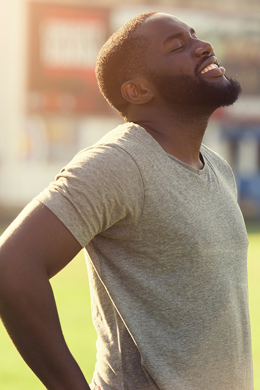 Allergic-Rhinitis-Treatment A black man in a t-shirt smiles and raises his face to the sun due to relief from allergies. Get treatment for allergic rhinitis from Guerda Johnson, FNP-C in Tyler East Texas Area.