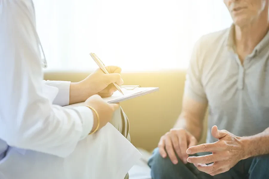 Annual-Wellness-Exams-Clinic A clinician takes notes while speaking with a patient. Schedule an annual wellness exam from Guerda Johnson, FNP-C in Tyler East Texas Area.