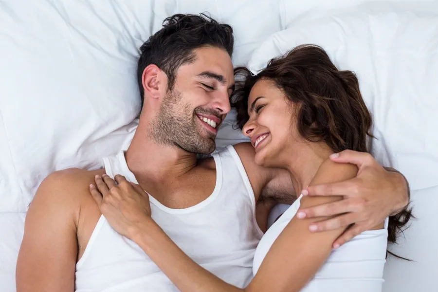 Apex-RF-for-ED-Clinic A couple lay in bed smiling at each other. Schedule Apex RF treatment for ED from Guerda Johnson, FNP-C in Tyler East Texas Area.