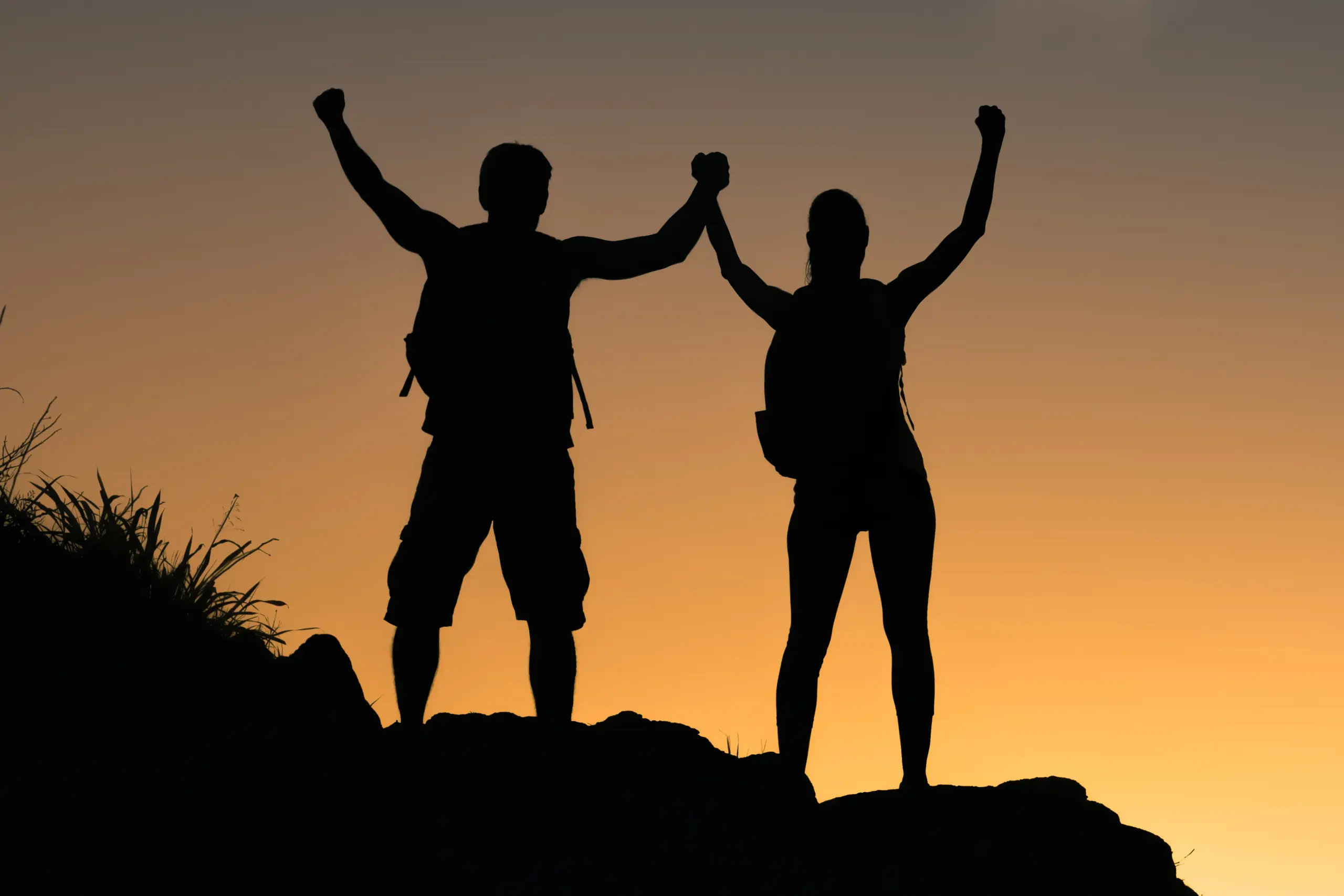 B-Lean-IV-Therapy-Clinic A couple completing a mountain climb hold their arms up to the sunset. Get IV therapy for weight loss from Guerda Johnson, FNP-C in Tyler East Texas Area.