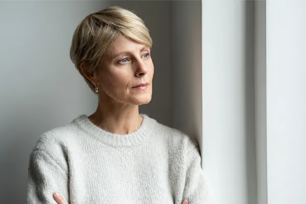 Chronic-Fatigue-Therapy A blond, middle-aged woman looks out the window with a tired expression. Get chronic fatigue treatment from Guerda Johnson, FNP-C in Tyler East Texas Area.