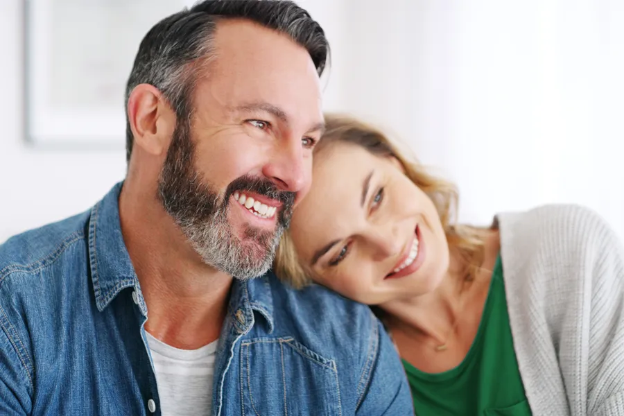 A middle-aged white couple in a bright white room smile and lay their heads on each other. Schedule concierge health and wellness services from Guerda Johnson, FNP-C in Tyler East Texas Area.