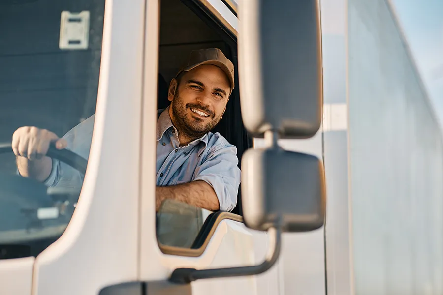 DOT-Physical-Exam-Clinic A smiling driver leans out the window of his freight truck. Get DOT physical exams from Guerda Johnson, FNP-C in Tyler East Texas Area.