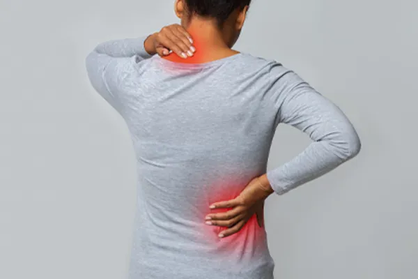 Fibromyalgia-Clinic An image from behind of a woman suffering from Fibromyalgia holding her hands on her neck and lower back. Get fibromyalgia care from Guerda Johnson, FNP-C in Tyler East Texas Area.