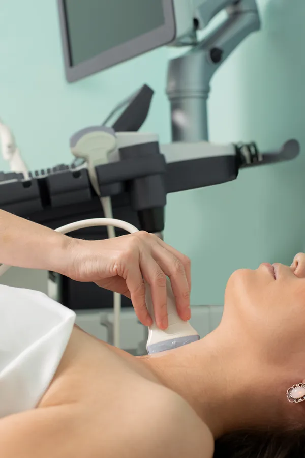Hashimotos-Thyroiditis-Treatment A woman gets a thyroid scan from a doctor in a clinic. Get help with Hashimoto's Thyroiditis from Guerda Johnson, FNP-C in Tyler East Texas Area.