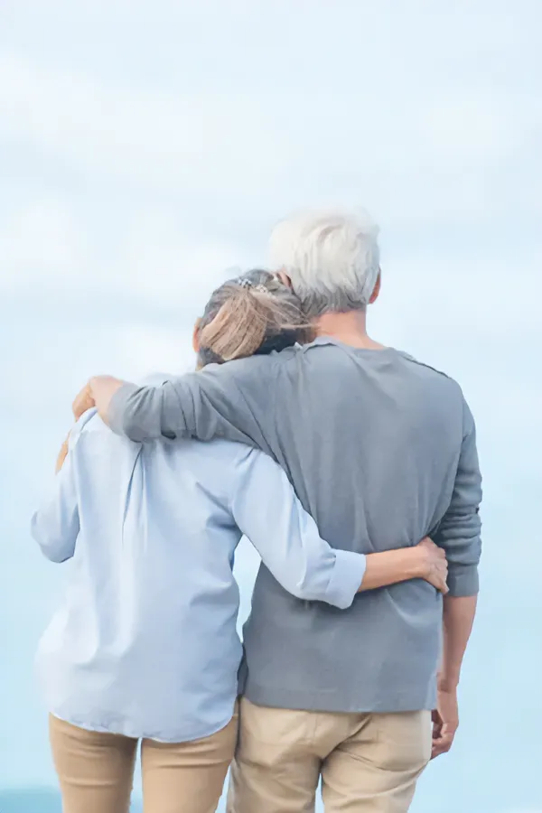 Migraine-and-Chronic-Pain-IV-Therapy-Treatment A mature couple look out over the ocean arm-in-arm. Get IV Therapy for migraine and chronic pain relief from Guerda Johnson, FNP-C in Tyler East Texas Area.
