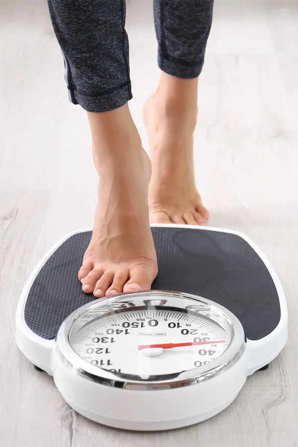 Obesity-Treatment Close up of feet stepping onto a scale. Receive expert functional medicine for obesity treatment by Guerda Johnson, FNP-C in Tyler East Texas Area.