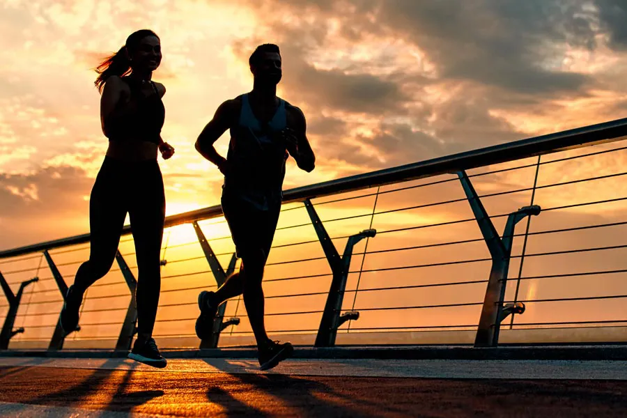 Performance-Enhancing-Peptides-Doctor A couple jogging on a bridge at sunrise, representing performance enhancing peptide therapy from Guerda Johnson, FNP-C in Tyler East Texas Area.