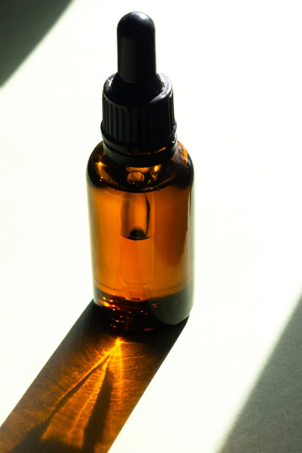 Performance-Enhancing-Peptides-Treatment A brown dropper bottle on a table lit by sunlight, representing performance enhancing peptide treatment from Guerda Johnson, FNP-C in Tyler East Texas Area.