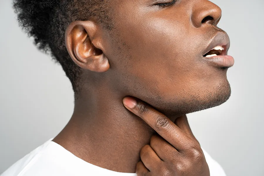 Thyroid-Disorder-Clinic-2 A black man massages his sore throat. Get treatment for thyroid disorders from Guerda Johnson, FNP-C in Tyler East Texas Area.